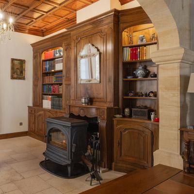 <h2>BIBLIOTHEQUE</h2>Boiserie décorative agencée en bibliothèque et côté droit ceintrée. Bois de noyer massif - finition cirée